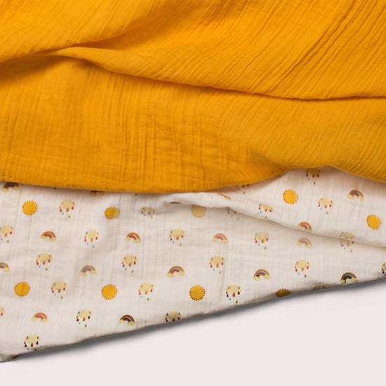 Little-Green-Radicals-Cream-And-Orange-Organic-Baby-Muslin-Set-2-Pack-With-Sunshine-and-Rainbow-Print-Closeup-View
