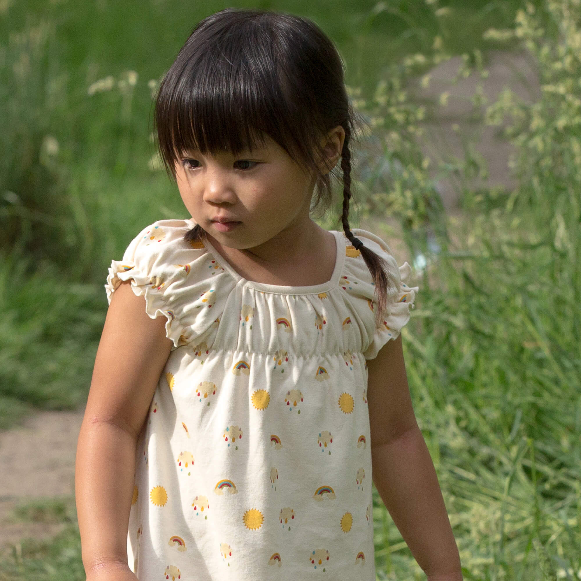 Little-Green-Radicals-Cream-Pocket-Playdays-Dress-With-Sunshine-And-Rainbow-Print-Kid-Closeup